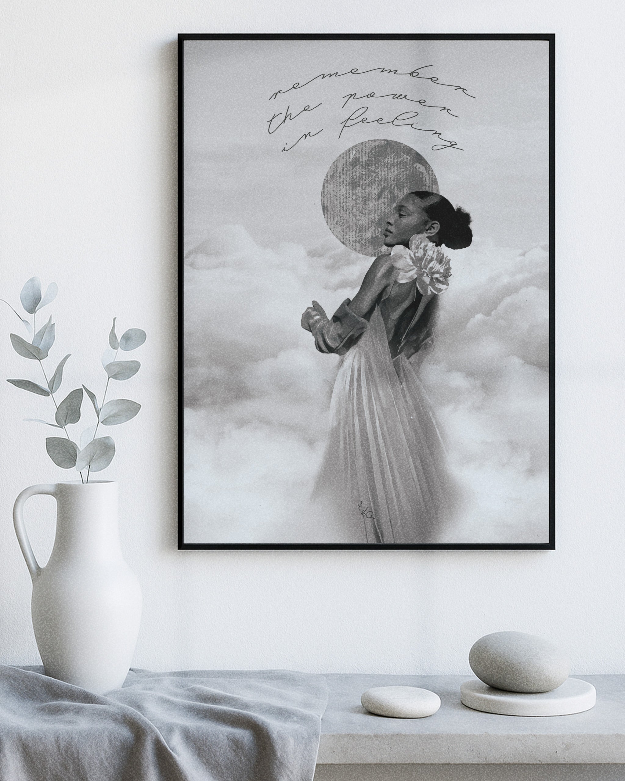 Framed modern decorative artwork of a woman in a dress with a moon in the sky, placed on a white wall above a table with decorative items.