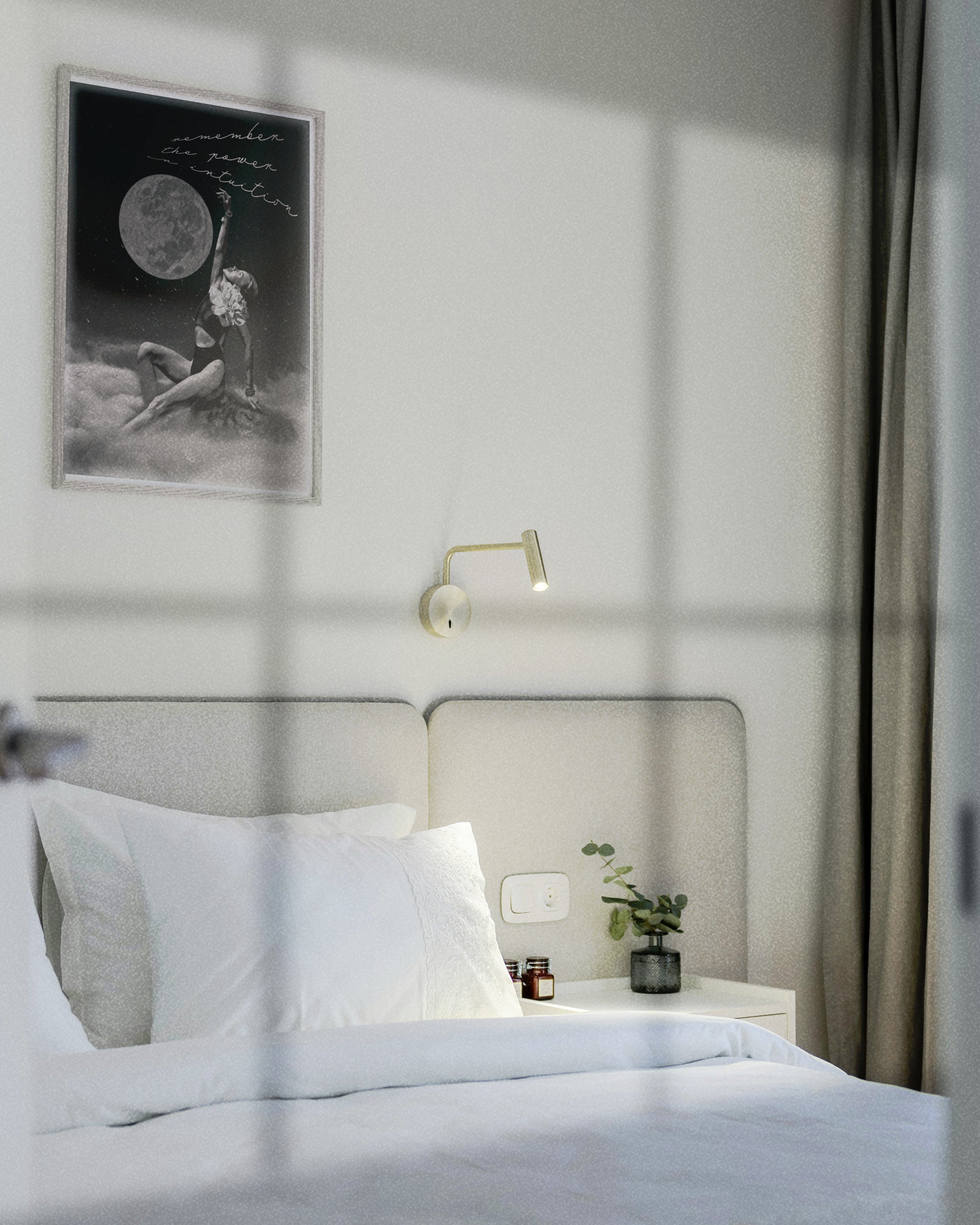 Neatly made bed in a bedroom with a wall lamp and framed The Shape Shifter dreamscape art