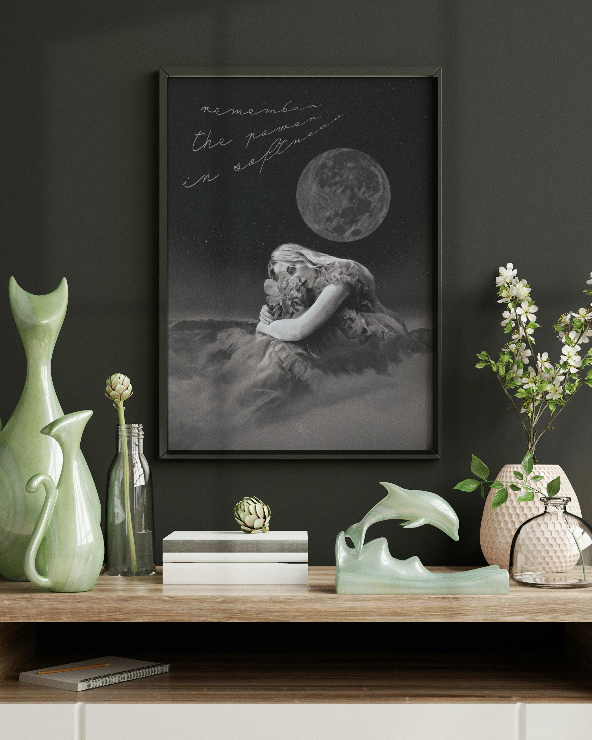 black white and grey wall art of a world changer framed in olive green frame over an olive wall over a brown wooden desk with decorations and flowers