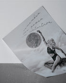 monochromatic wall art of a light shifter,  a woman in a swimsuit and text 'Remember the power in intuition' on a textured surface.