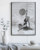 Framed women wall art for bedroom of a woman in a swimsuit with a moon above, on a white wall with decor items below.