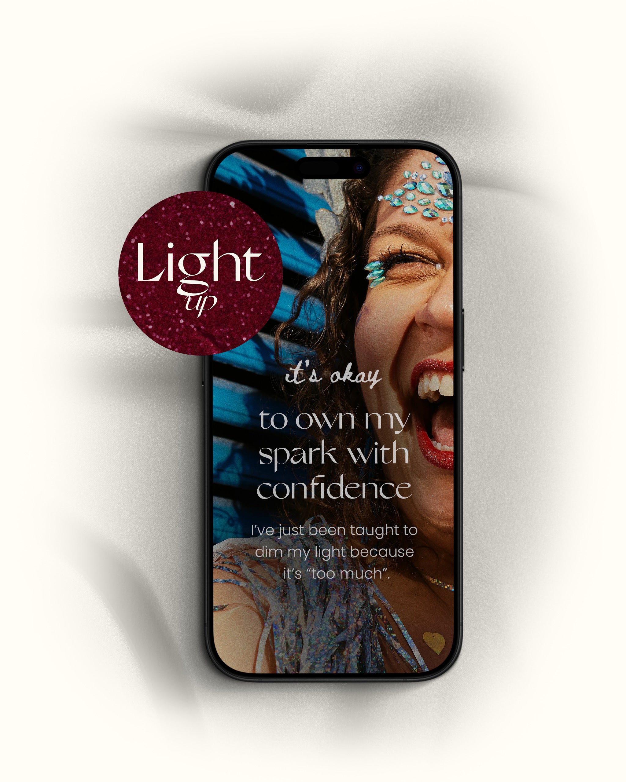 "light up" christmas self care iphone wallpaper with the title "it's okay to own my spark with confidence" with an image of woman smiling, shown on an iphone on a white background